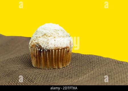 Cupcake auf einem isolierten Hintergrund als Hintergrund für den Text. Ein Muffin in einer Papierform und bestreut mit Puderzucker Stockfoto