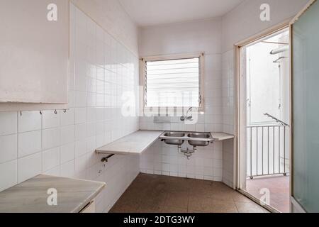 Helle leere Küche mit Fliesenboden und Wänden vor der Renovierung Stockfoto