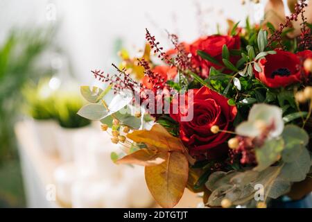 Floraler Hintergrund, Textur. Rotes Bouquet, Blumenarrangement von Floristen mit roten Rosen, Mohnblumen und Eukalyptusblättern aus nächster Nähe, Makro Stockfoto