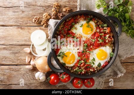 Adjarian Frühstück Chirbuli von Spiegelei mit Tomaten, Zwiebeln und Walnüssen Nahaufnahme in einer Pfanne auf dem Tisch. Horizontale Ansicht von oben Stockfoto