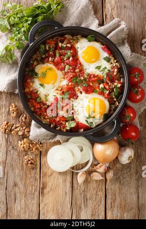 Georgische Frühstück Spiegelei mit Tomaten, Zwiebeln und Walnüssen Nahaufnahme in einer Pfanne auf dem Tisch. Vertikale Ansicht von oben Stockfoto