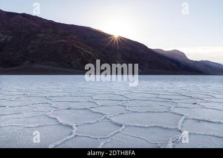 Sonnenaufgang über dem Badwater Basin, Death Valley, Kalifornien. Beckenboden ist mit weißen Salzablagerungen in geometrischen Formen bedeckt. Stockfoto