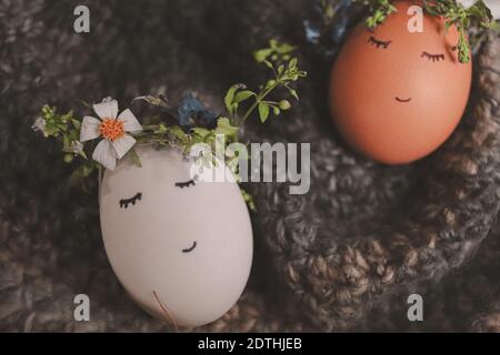 Niedliche Eier tragen Blumenkronen mit gezeichneten Gesichtern als Dekoration Für Ostern und das Kommen des Frühlings Stockfoto