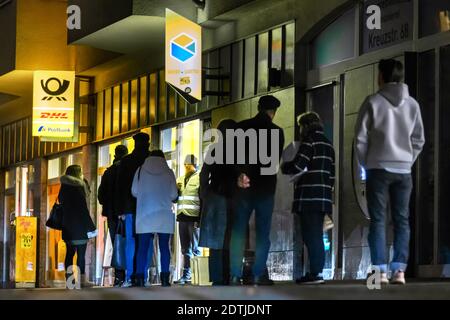 Dortmund, 18. Dezember 2020: Kunden warten auf dem Bürgersteig vor einer Filiale der Deutschen Post / DHL in Dortmund. Aufgrund der Einschränkungen der zweiten Sperrung der Corona-Pandemie dürfen nur 3 Kunden gleichzeitig in dieser Filiale bleiben. Stockfoto