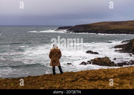 Die Frau, die den Blick auf den atlantischen Ozean Sturm am Ufer von Malin Beg genießt, kleines Dorf Gaeltacht südlich von Glencolumbkille, Grafschaft Donegal, Irland Stockfoto