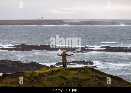 Eine Frau genießt einen Blick auf den atlantischen Sturm am Ufer von Malin Beg, in dem kleinen Dorf Gaeltacht, südlich von Glencolumbkille, Co.Donegal, Irland Stockfoto