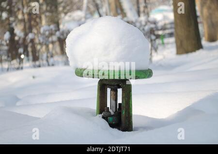 Wasserhahn für die Bewässerung der Straße mit einer großen Kappe Schnee im Winter Stockfoto