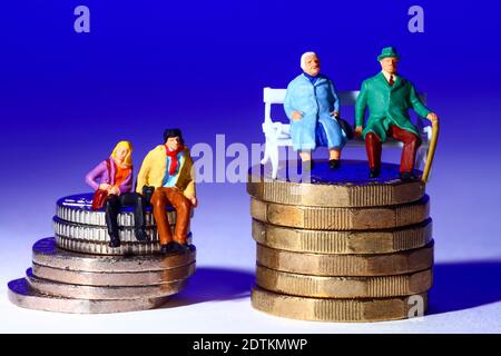 Konzeptuelles Miniaturbild eine Figur Paare saßen auf Münzen Isoliert vor blauem Hintergrund Stockfoto