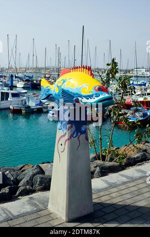 Corralejo, Fuerteventura, Spanien - 02 April 2017: Fisch Skulptur und Boote im Yachthafen der Stadt auf den Kanarischen Inseln Stockfoto