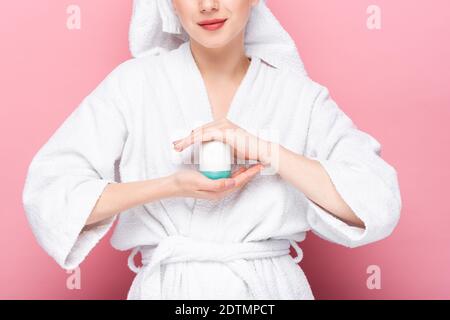 Verkürzte Ansicht der jungen Frau im Bademantel hält Deodorant an Rosa Stockfoto