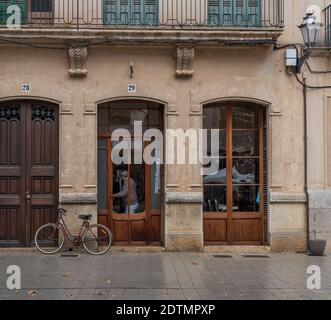 Llucmajor, Spanien; dezember 17 2020: Eingang eines alten Friseurs mit einem Fahrrad davor geparkt, und ein Kunde verlässt das Gelände mit einem Stockfoto