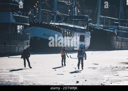 Drei Jungen spielen Eishockey auf dem gefrorenen Aura River in Turku, Finnland Stockfoto