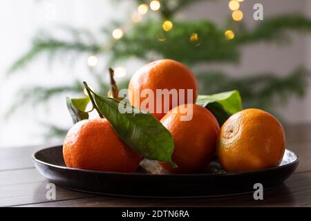Teller mit Mandarinenfrüchten mit Blättern Stockfoto