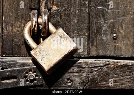 Alte Holztür mit Vorhängeschloss verriegelt. Stockfoto