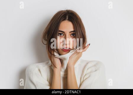 Gemütlich. Portrait der schönen Brünette Frau in komfortablen weichen Longsleeve isoliert auf weißem Studio-Hintergrund. Wohnkomfort, Emotionen, Gesichtsausdruck, Winterstimmung Konzept. Copyspace. Stockfoto