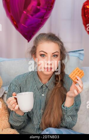 Überrascht junge Frau mit langen Haaren hat Frühstück im Bett am Valentinstag. Hochwertige Fotos Stockfoto