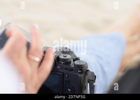 Die Frau, die die Einstellungen der schwarzen Digitalkamera anpasst Stockfoto