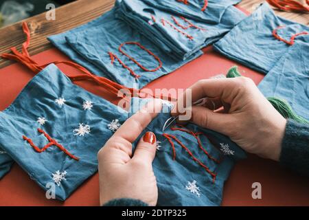 Stoffbeutel für Weihnachtsgeschenke und handgefertigte Zahlen mit Dekorationen auf dem Tisch. Handgemachtes Adventskalender für Weihnachten Stockfoto