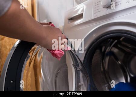 Frauenhände mit Tuch die Reinigung einer Waschmaschine nach dem Waschen ist vorbei. Stockfoto