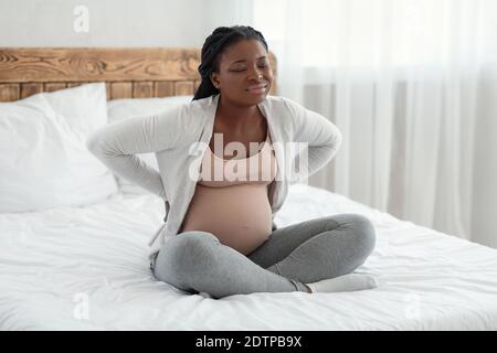 Schwangerschaftskomplikationen. Schwarze Werdende Mutter Leidet Unter Rückenschmerzen Zu Hause Stockfoto