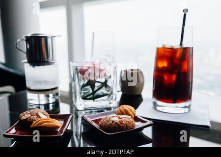 Vietnamesischer Kaffee mit heißem und vereisten Filter und Keksen auf dem Tisch. Stockfoto