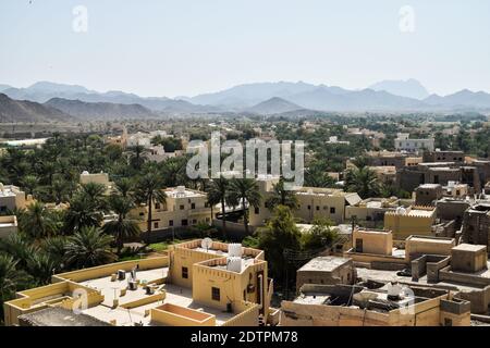 BAHLA, OMAN - 16. FEBRUAR 2018: Blick von Bahla Fort auf die Stadt. Gebäude, Palmen und Berge. Stockfoto