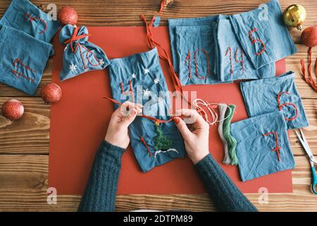 Stoffbeutel für Weihnachtsgeschenke und handgefertigte Zahlen mit Dekorationen auf dem Tisch. Handgemachtes Adventskalender für Weihnachten Stockfoto