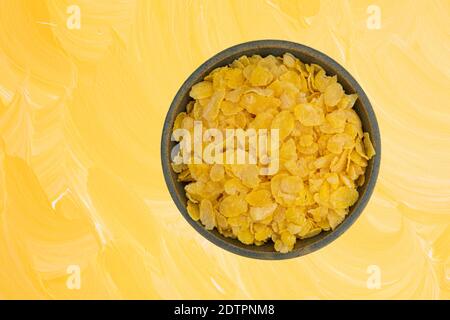 Draufsicht auf eine Schüssel mit trockenem getoastetem Maiskorn, isoliert auf gelbem Hintergrund. Stockfoto