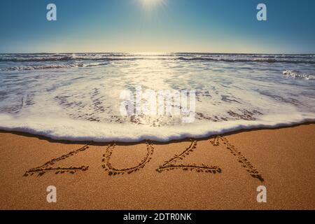 Happy New Year 2021 Konzept, Schriftzug am Strand. Geschriebener Text am Strand bei Sonnenaufgang. Stockfoto