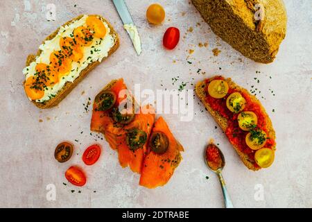 Offene Sandwiches aus braunem Vollbrot. Scheiben knusprig gerundetes Brot mit Tomaten, geräuchertem Lachs und Käse.Frühstückszubereitung Stockfoto