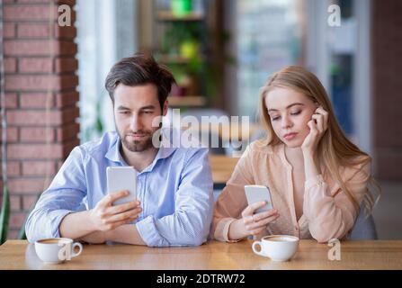 Smartphone sucht und Phubbing Konzept. Junges Paar auf langweiligen Datum, stecken in Gadgets, vernachlässigen einander im Café Stockfoto