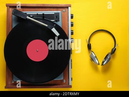 Retro Vinyl Plattenspieler, Kopfhörer auf gelbem Hintergrund. Draufsicht Stockfoto