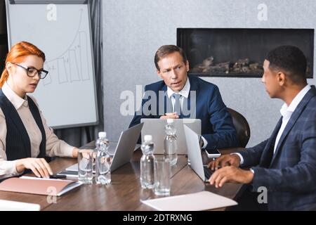 Serious Executive im Gespräch mit afroamerikanischen Geschäftsmann während der Diskussion in Tagungsraum Stockfoto