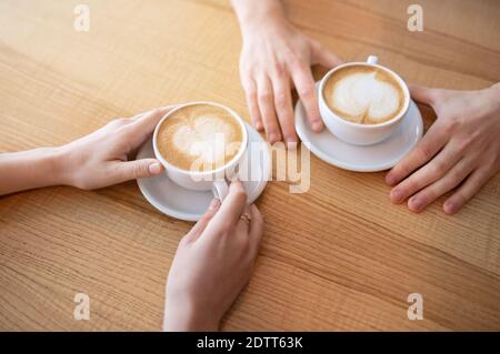 Cropped Ansicht von jungen Paar mit Kaffee mit Herz geformt Schaum am Tisch im Café Stockfoto