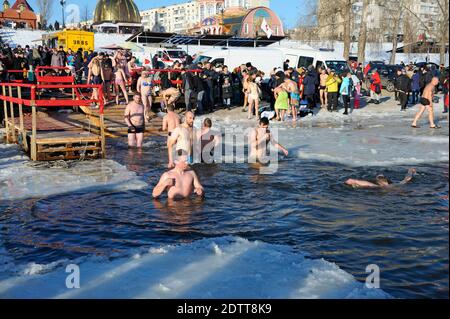 Menschen schwimmen in einem Eisloch während des Dreikönigsfestes auf dem Fluss Dnjepr, Sviato-Pokrovskiy Kathedrale auf einem Hintergrund. Januar 19, 2019. Kiew, Ukr Stockfoto