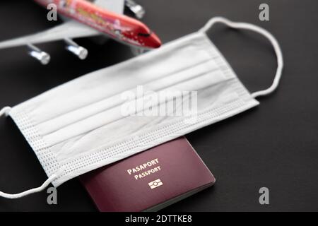 Sichere Reise während des Virus covid-19 Pandemie . Flugzeugmodell mit Gesichtsmaske, Reisepass, isoliert auf schwarzem Hintergrund, Draufsicht. Niemand, keine Leute, s Stockfoto