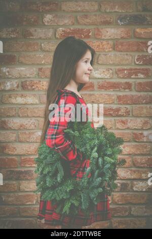 Kleines Mädchen in rot Tartan Kleid hält grün handgemachte Weihnachten Kranz Stockfoto