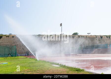 Sprinkler bewässern das Gras eines örtlichen Sportstadions. Stockfoto