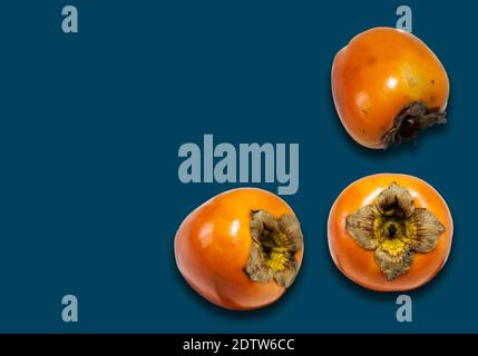 Frische reife ganze Persimmon, sharon auf blauem Hintergrund mit Platz für Text, gesunde vegetarische Ernährung Draufsicht Stockfoto