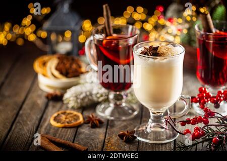 Frischer gelber Eierwein und fruchtiger roter Glühwein mit weihnachtlicher Dekoration. Auswahl an alkoholischen Heißgetränken im Herbst oder Winter Stockfoto