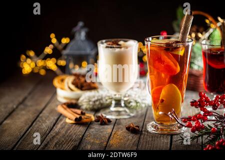 Frischer gelber Eierwein, Grog und fruchtiger roter Glühwein mit weihnachtlicher Dekoration. Auswahl an alkoholischen Heißgetränken im Herbst oder Winter Stockfoto