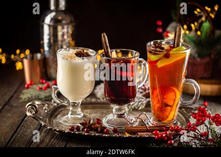 Frischer gelber Eierwein, Grog und fruchtiger roter Glühwein mit weihnachtlicher Dekoration. Auswahl an alkoholischen Heißgetränken im Herbst oder Winter Stockfoto