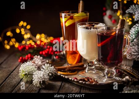 Frischer gelber Eierwein, Grog und fruchtiger roter Glühwein mit weihnachtlicher Dekoration. Auswahl an alkoholischen Heißgetränken im Herbst oder Winter Stockfoto