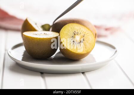 Halbierte reife gelbe Kiwi-Früchte auf dem Teller. Stockfoto