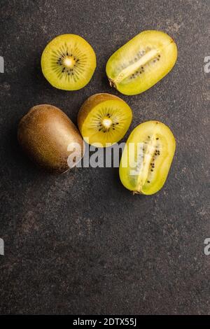 Halbierte reife gelbe Kiwi-Frucht auf schwarzem Tisch. Draufsicht. Stockfoto