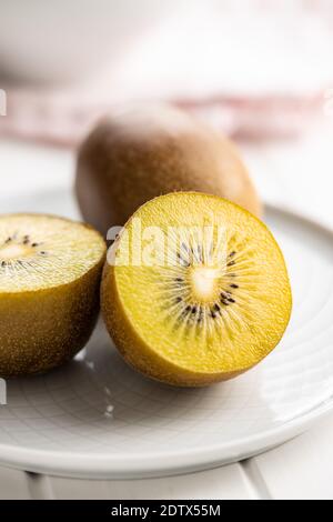 Halbierte reife gelbe Kiwi-Früchte auf dem Teller. Stockfoto