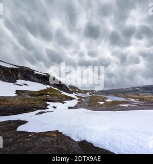 Typisch norwegische Landschaft mit schneebedeckten Bergen und Clear Lake in der Nähe der berühmten Aurlandsvegen (Bjorgavegen), Mountain Road, Aurland, Norwegen. Stockfoto