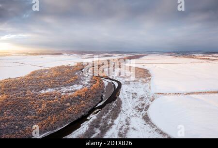 Flug durch majestätischen Fluss, gefrorenen Wald und frostigen Winterfeldern bei Sonnenaufgang. Landschaftsfotografie Stockfoto