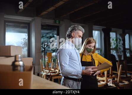 Frustrierter Besitzer mit Kellnerin in geschlossenem Cafe, kleine Unternehmen geschlossen wegen Coronavirus. Stockfoto