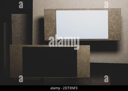 Geschäftskonzept. Schwarz-weiße Visitenkarten-Vorlagen auf verschiedenen Holzblöcken Mosaik platziert, die wirft schwarze Schatten auf dunklen Hintergrund Stockfoto